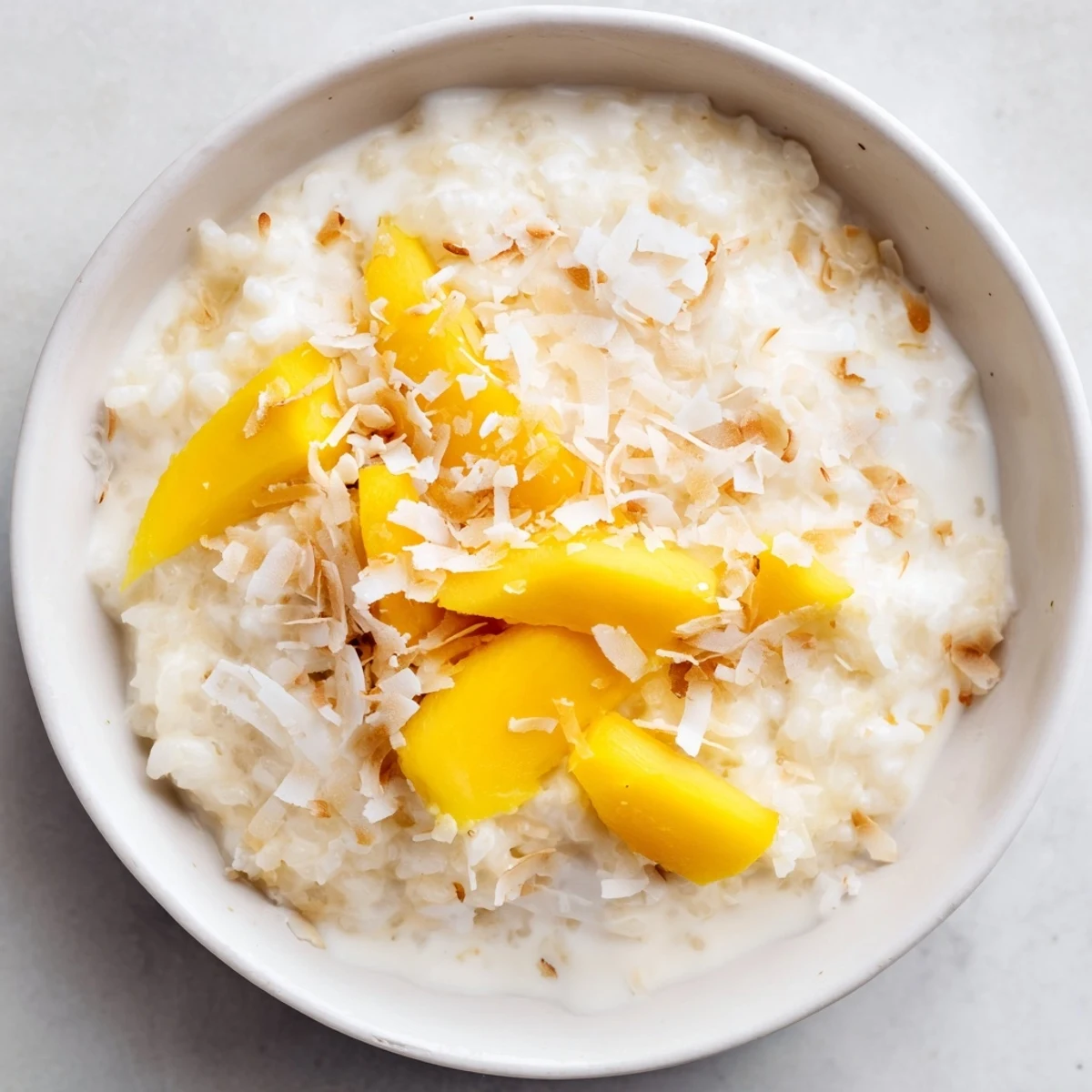 Spoonful of rich vanilla coconut rice pudding drizzled with coconut milk and cinnamon