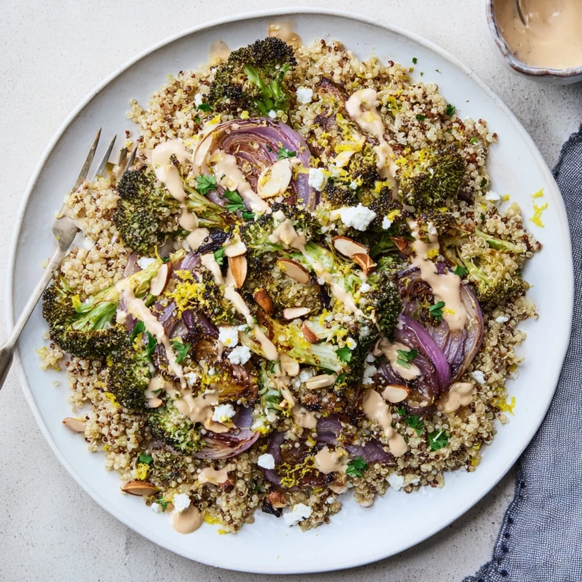 Warm grain salad featuring caramelized broccoli florets tossed in tangy tahini lemon sauce with toasted almonds