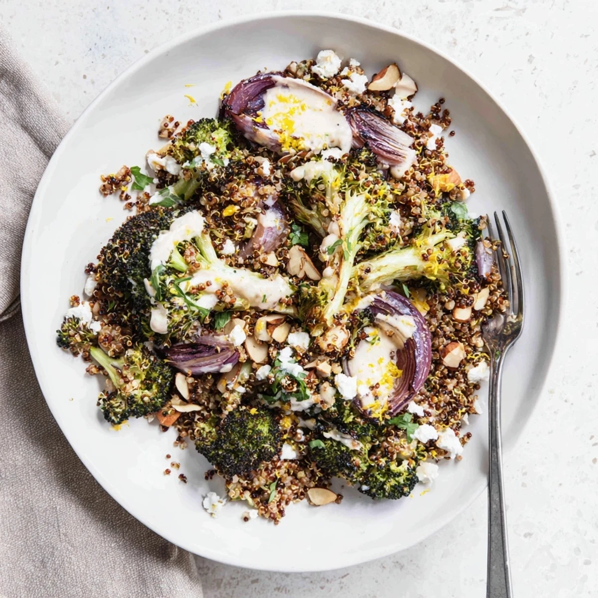 Golden roasted broccoli and fluffy quinoa bowl drizzled with creamy lemon tahini dressing and fresh parsley