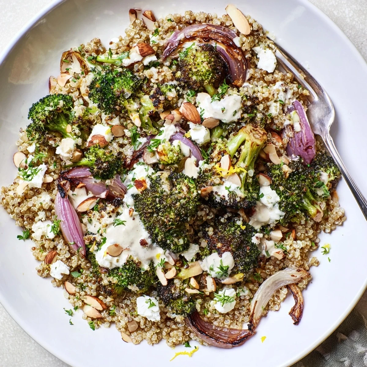 Hearty quinoa and roasted vegetable salad topped with bright lemon zest and nutty sesame tahini dressing