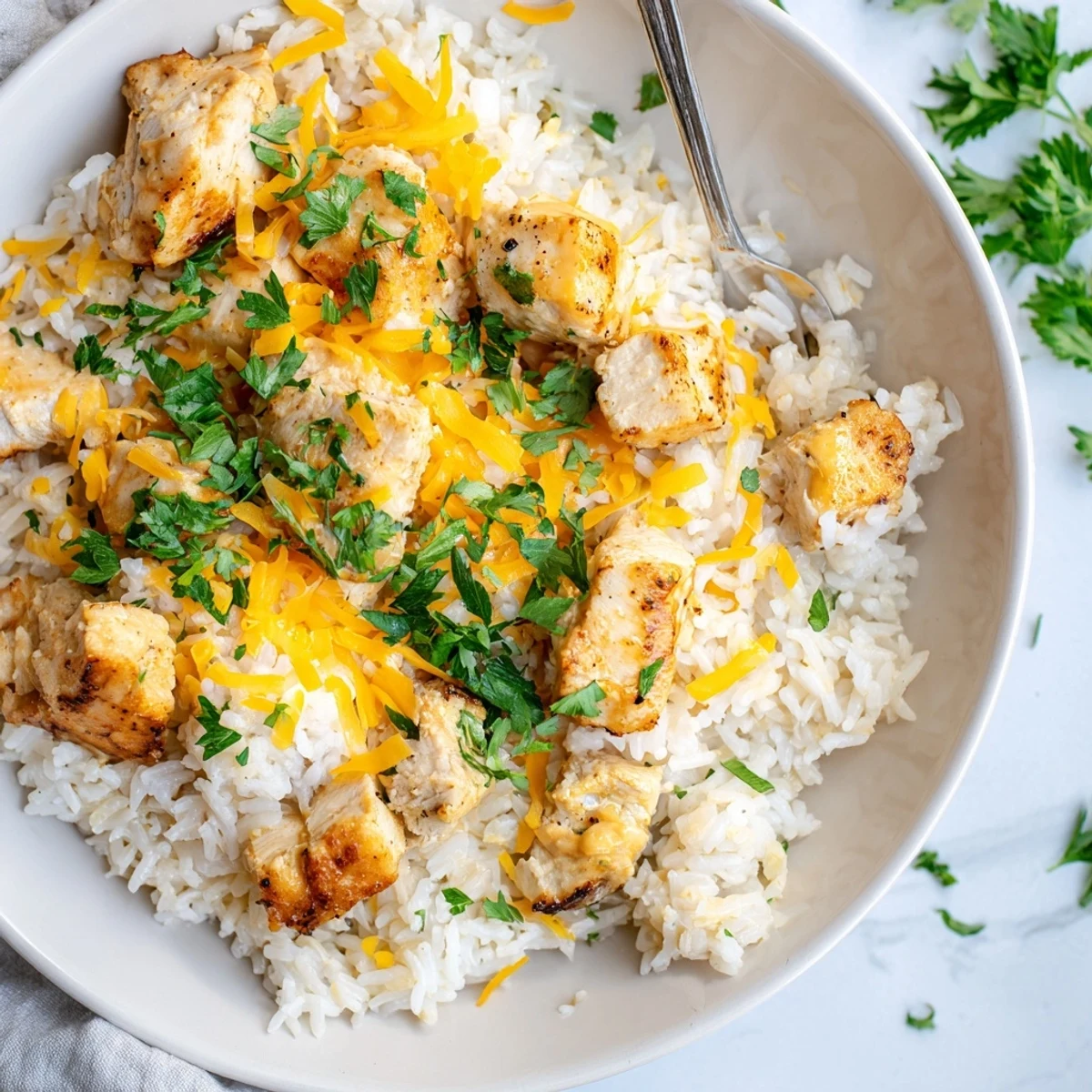 Golden brown chicken breasts nestled in creamy rice with melted cheddar cheese and fresh parsley garnish