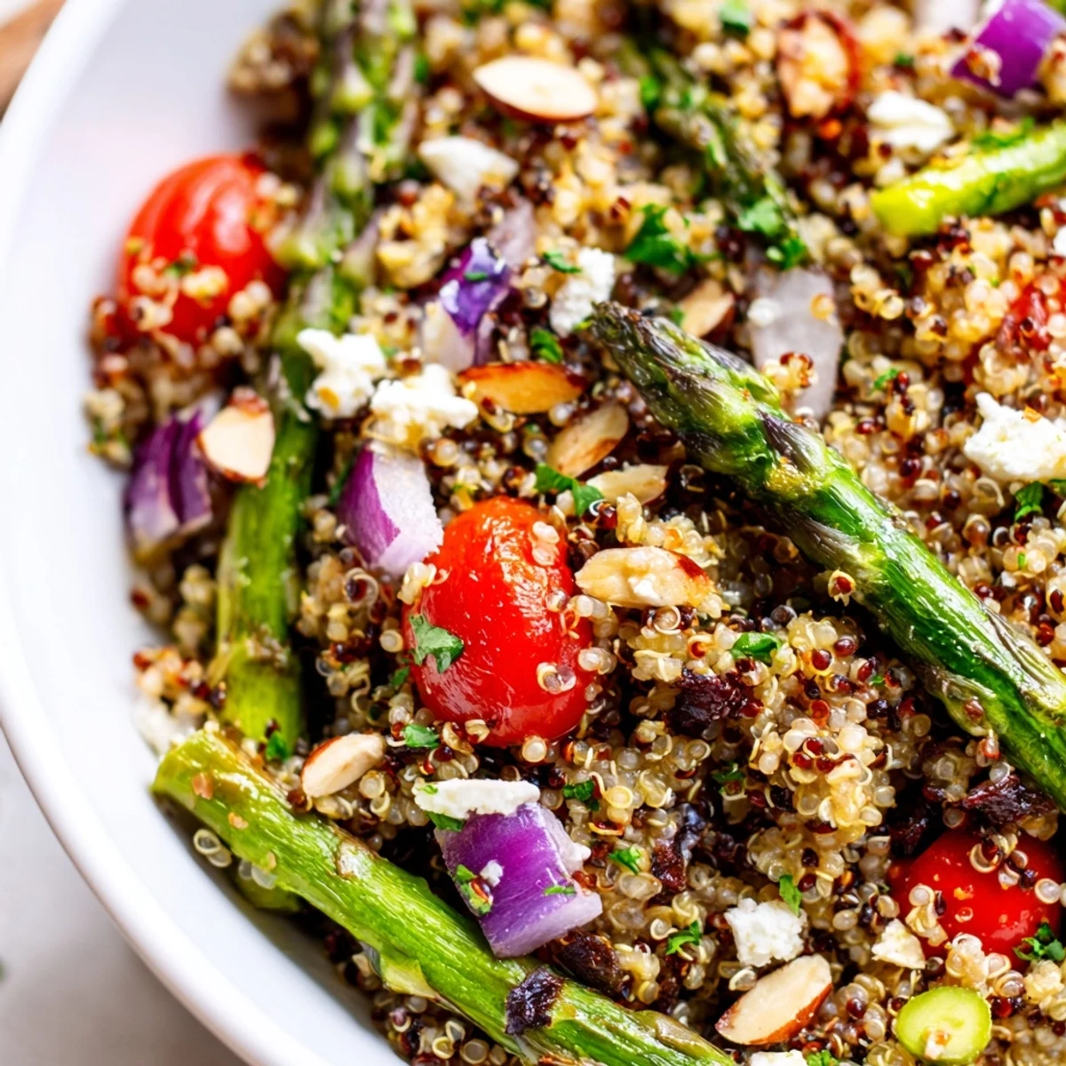 Fluffy quinoa mixed with tender roasted asparagus pieces and bright red cherry tomatoes drizzled with zesty lemon dressing