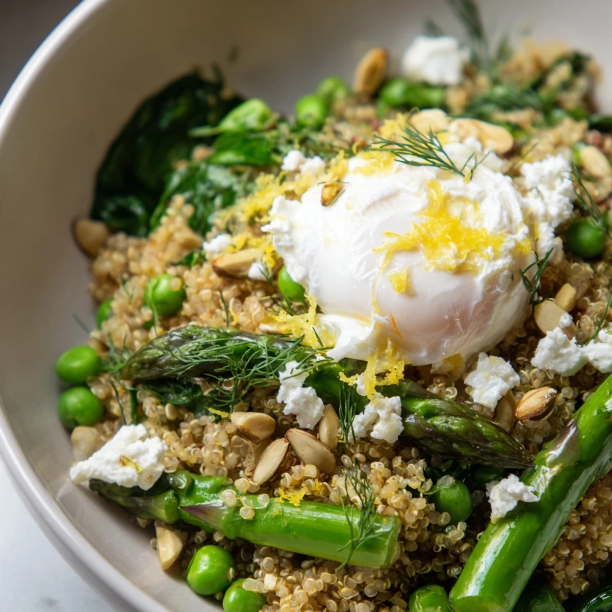 Fluffy quinoa breakfast bowl with bright green asparagus, sweet peas, and lemon herb dressing drizzle