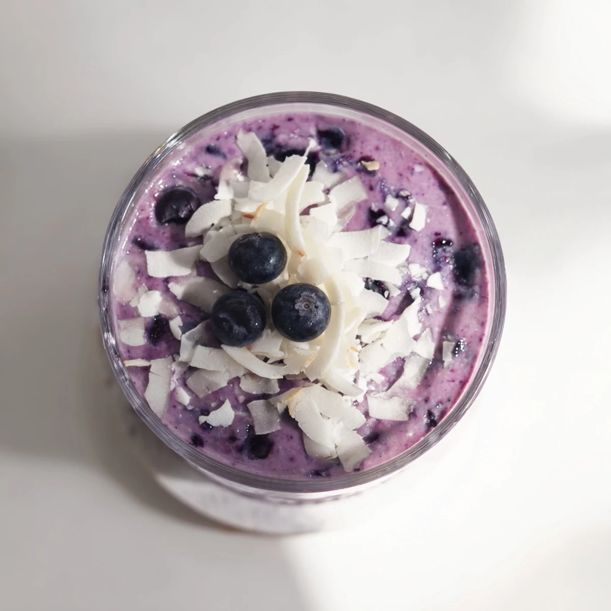 Creamy vegan smoothie blended with frozen banana, sweet blueberries and coconut milk in a tall glass