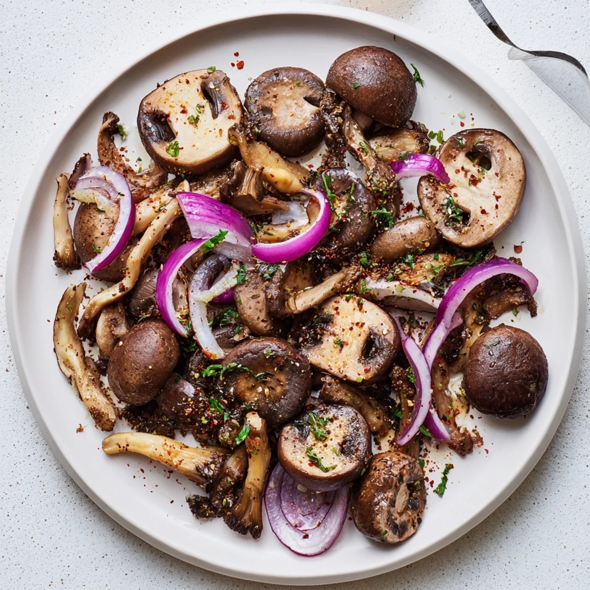 Vegan smoky roasted mushroom medley showing tender browned caps with caramelized red onion pieces