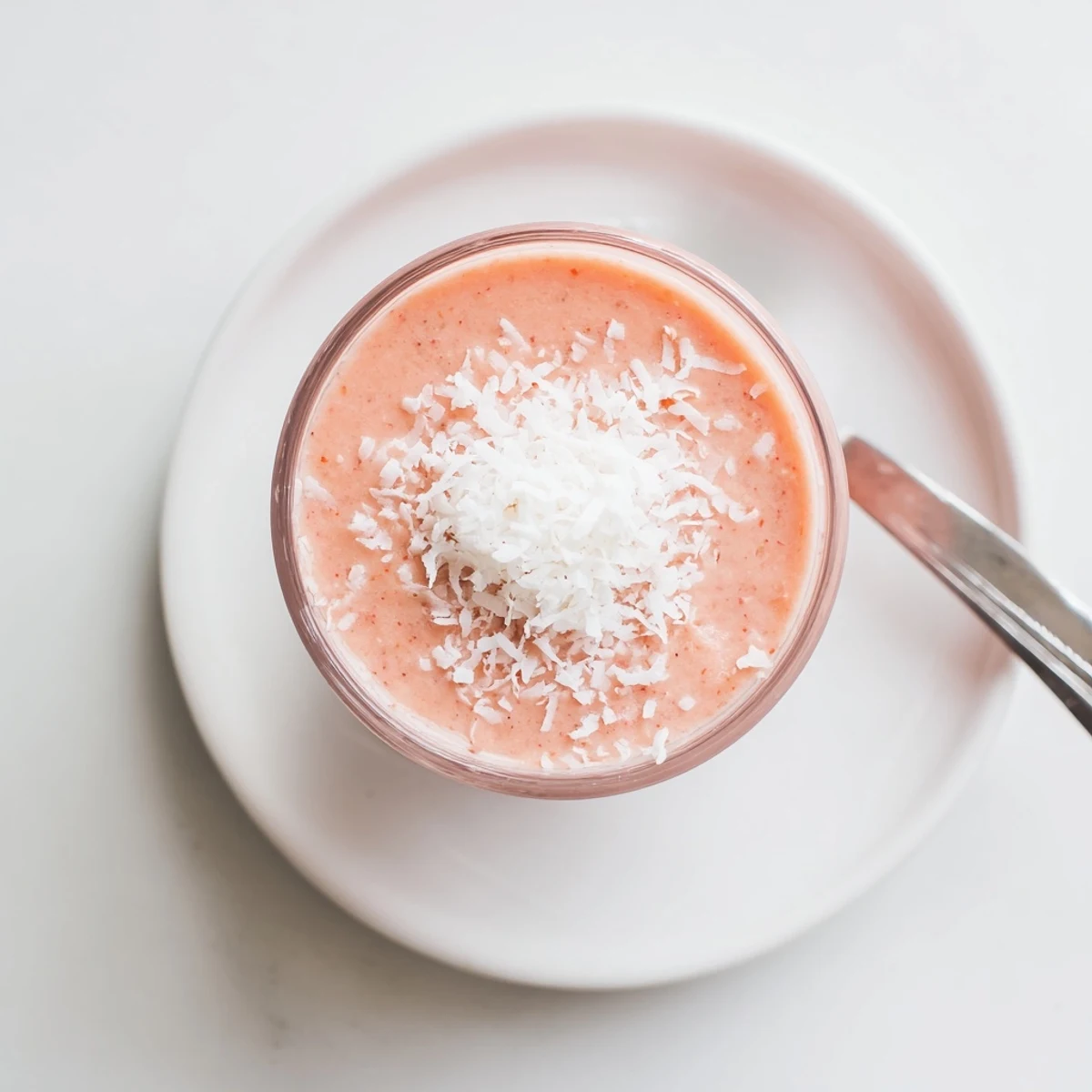 Thick Peach Raspberry Coconut Smoothie topped with shredded coconut for a refreshing breakfast