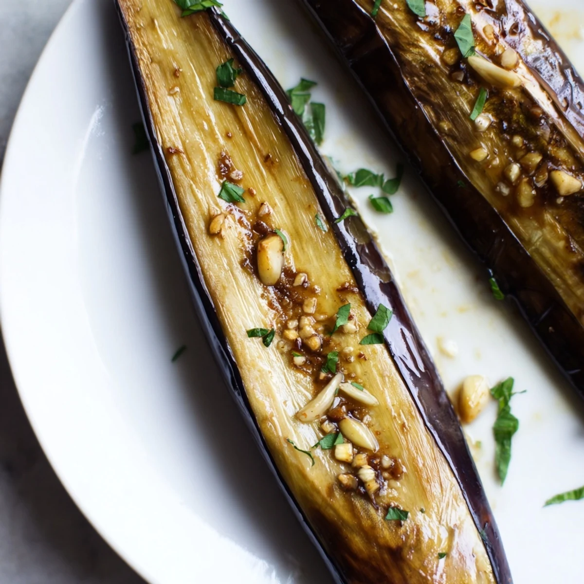 Smoky Roasted Eggplant Spears glistening with olive oil, caramelized edges, parsley garnish.