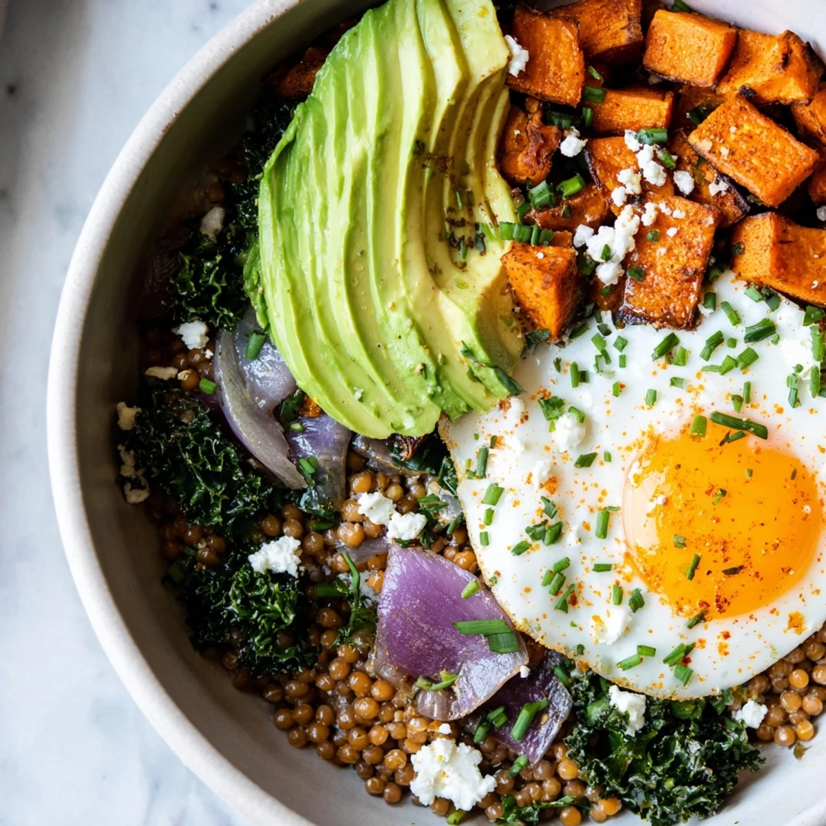 Roasted sweet potato and kale sorghum breakfast bowl served with sliced avocado on a rustic wooden table
