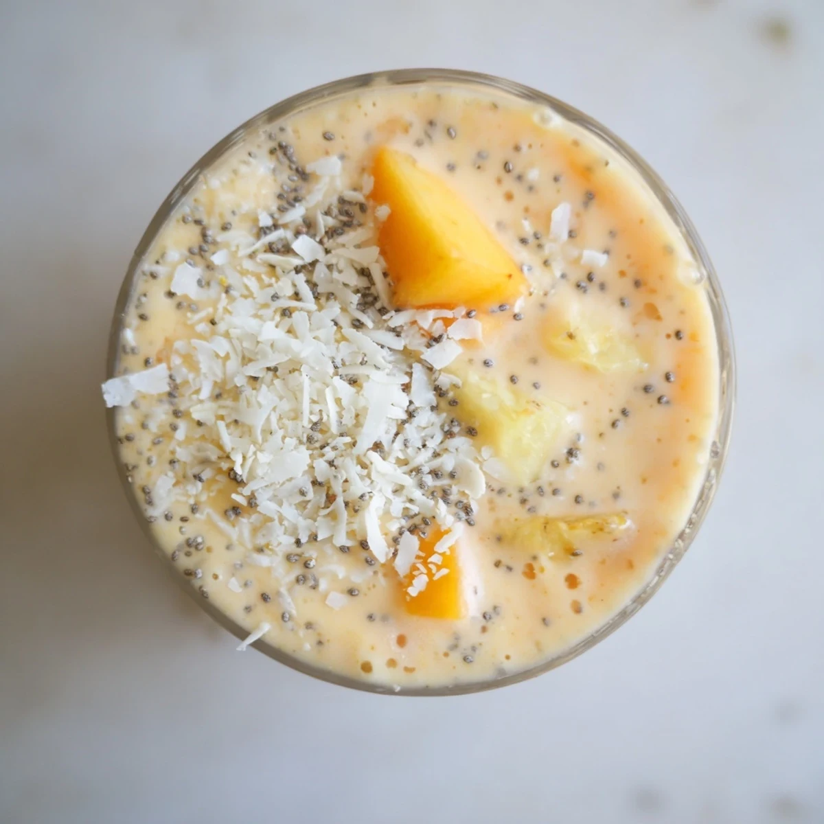 Golden peach pineapple coconut smoothie poured tall and topped with shredded coconut