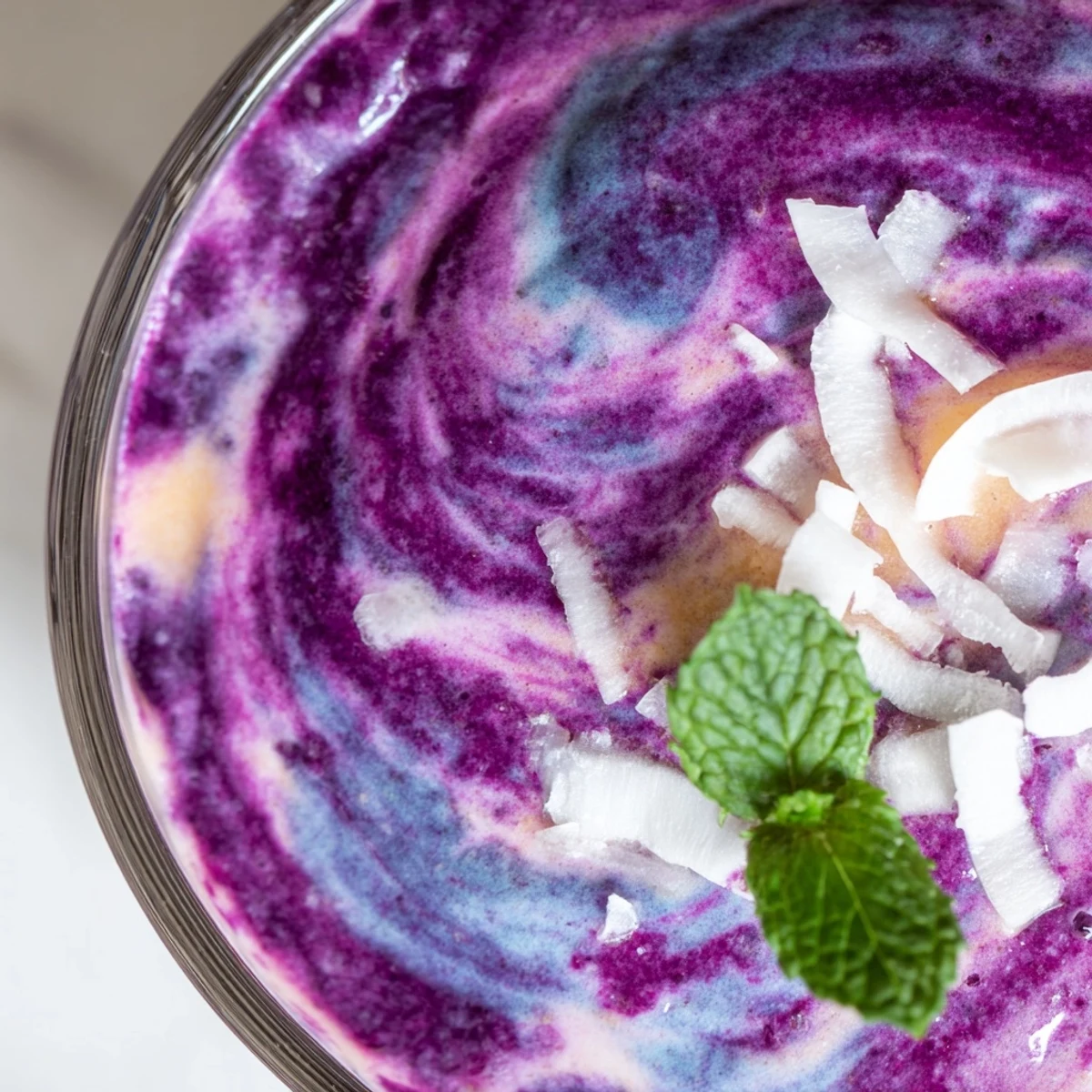 A thick blueberry peach coconut smoothie swirling with deep purple and golden hues served in a mason jar.