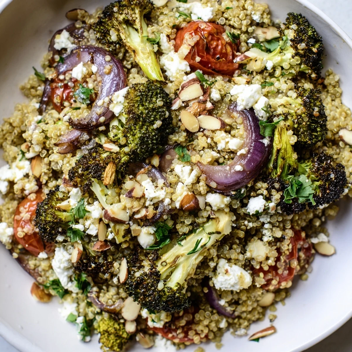 Warm quinoa and roasted broccoli salad topped with toasted almonds and crumbled feta cheese