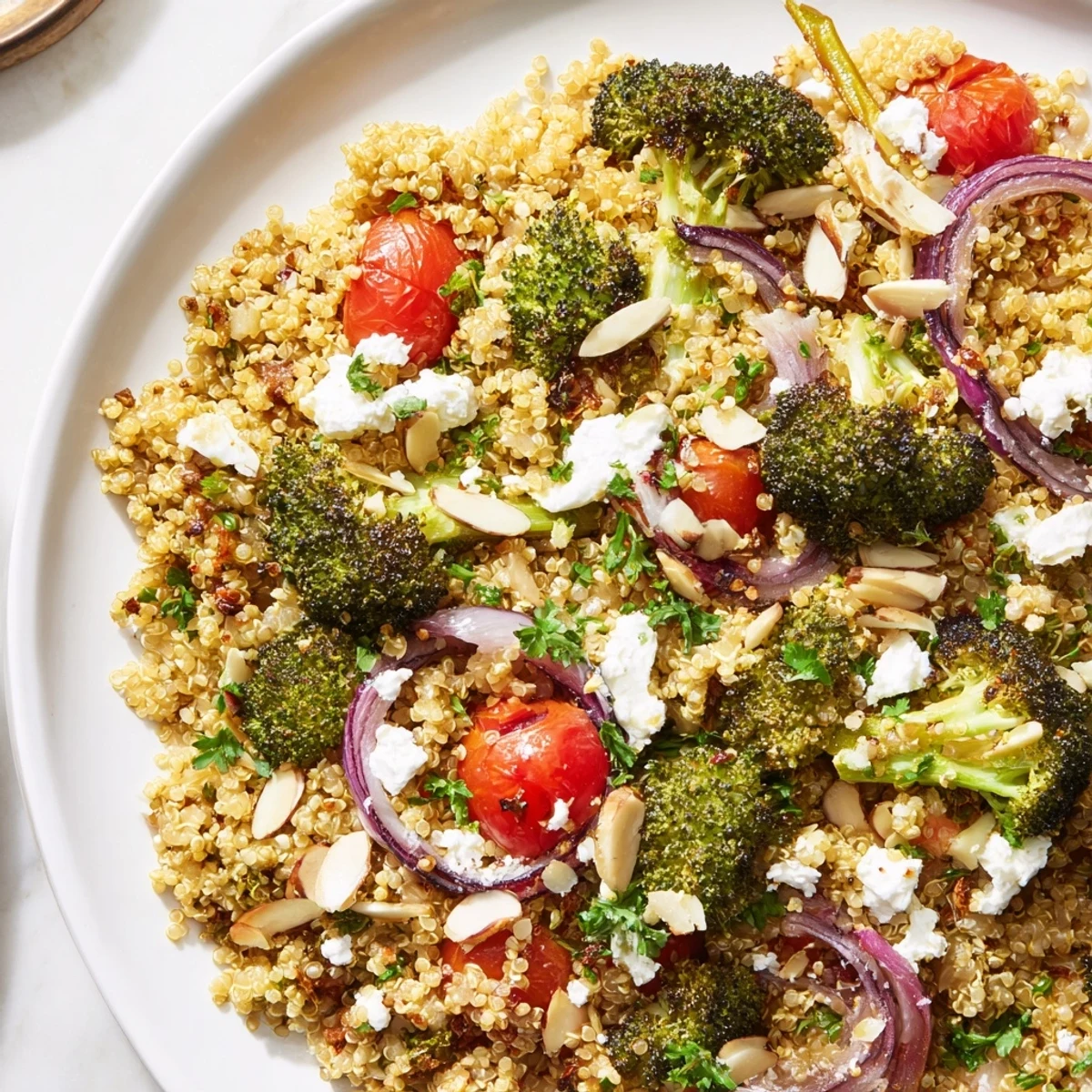 Colorful warm quinoa and roasted broccoli salad with cherry tomatoes, fresh herbs, and tahini drizzle