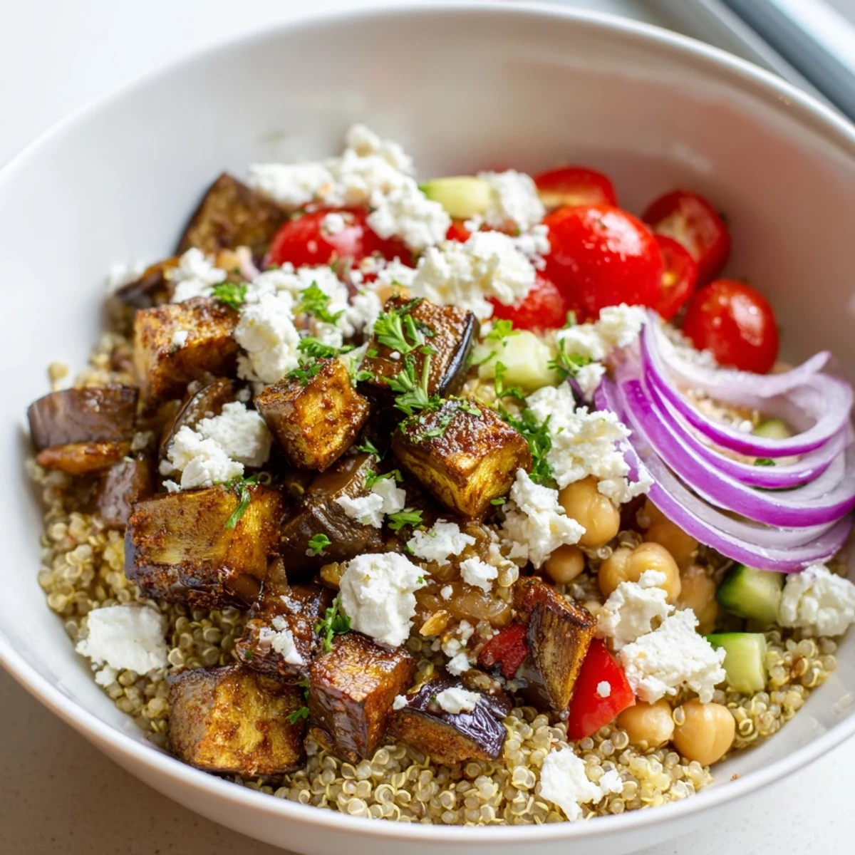 Smoky roasted eggplant and fluffy quinoa grain bowl drizzled with zesty Mediterranean dressing