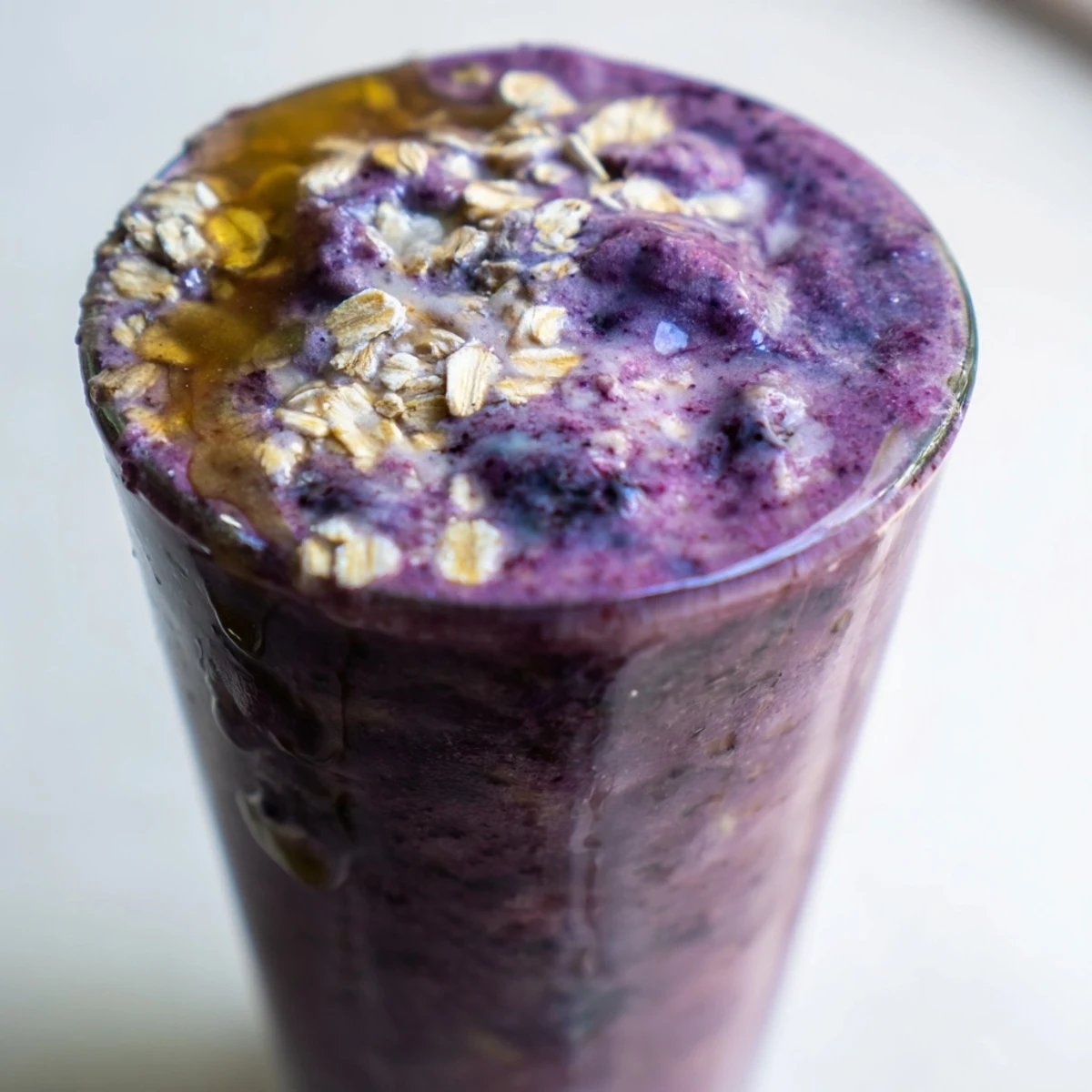 Thick and creamy blueberry mango oat smoothie swirled with vibrant purple and golden hues