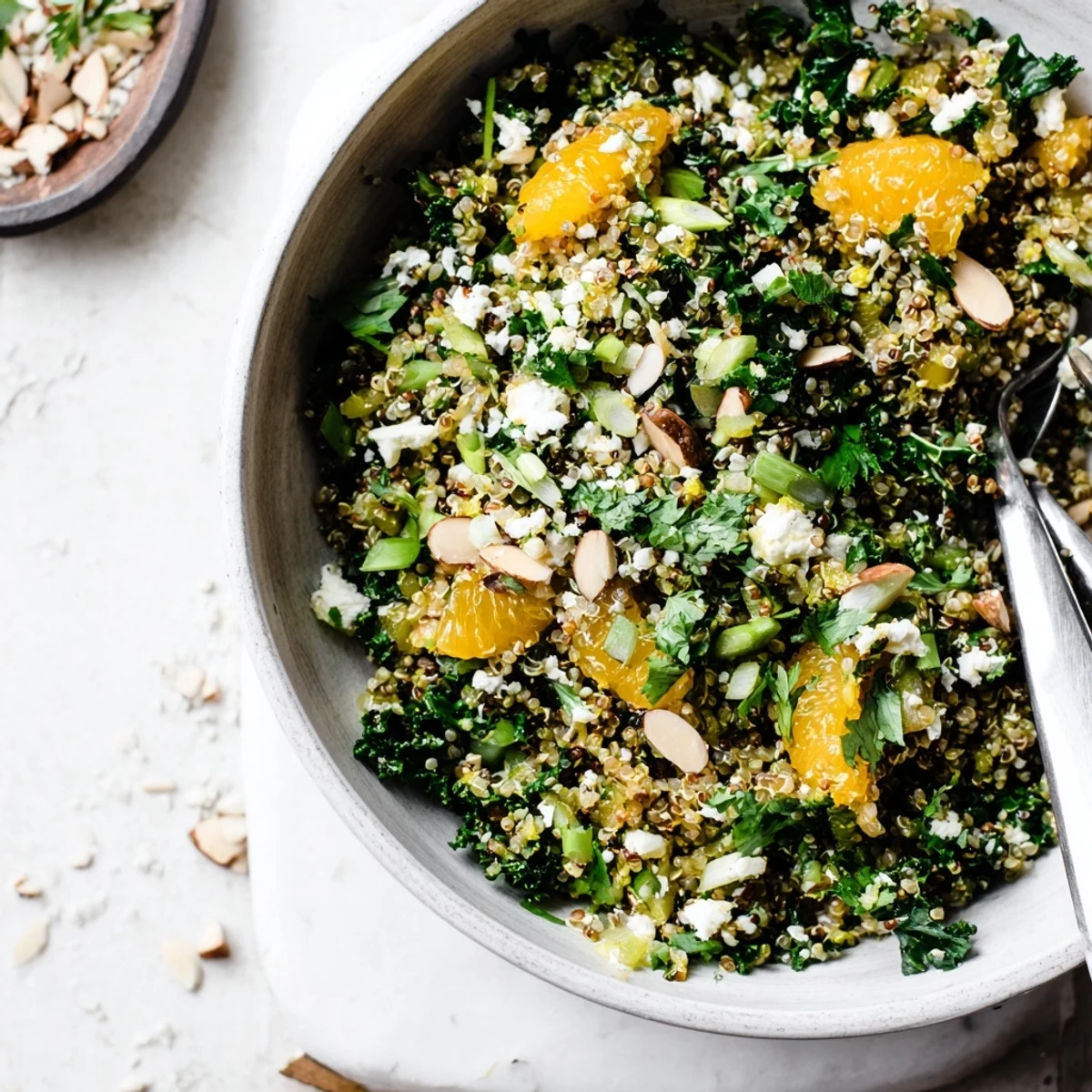 Colorful bowl of citrus herb quinoa and kale salad topped with almonds.