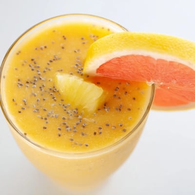 A tall glass of refreshing Citrus Ginger Smoothie garnished with chia seeds and an orange slice.