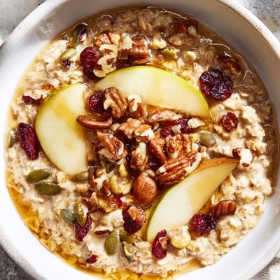 Hearty Maple Seasonal Nut Porridge with creamy oats, pecans, and fresh berries steaming in a rustic bowl.