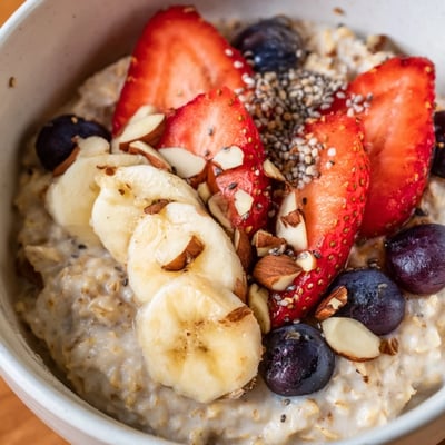 Creamy Fruit Topped Porridge served hot in a bowl, topped with sliced strawberries and bananas.
