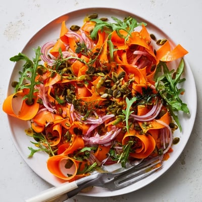 Sunlit Citrus Roasted Carrot Ribbon Salad features tender carrots and arugula on a white platter.