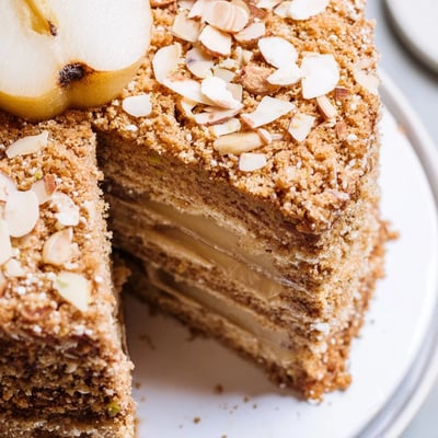 Fragrant Cardamom Pear Almond Cake on a white plate with Greek yogurt dollop.