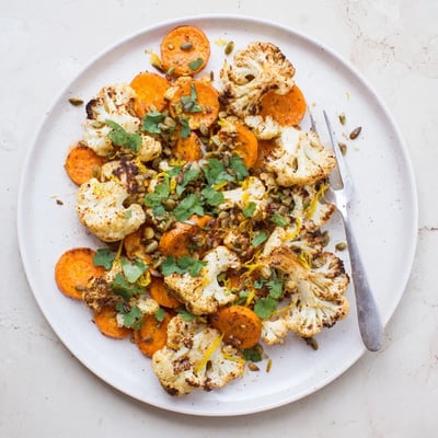 Warm Spiced Cauliflower and Carrot Medley served alongside grilled chicken, garnished with lemon zest for brightness.