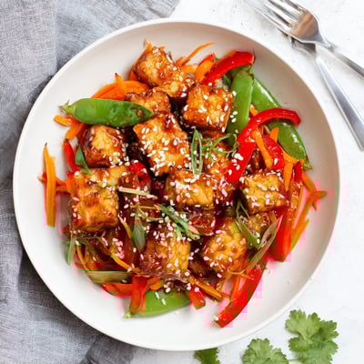 Aromatic Ginger Garlic Tempeh Skillet simmering in glossy sauce, garnished with green onions and sesame seeds.